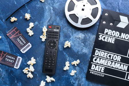Modern TV remote control, film reel, clapperboard and cinema tickets on color backgroundの写真素材