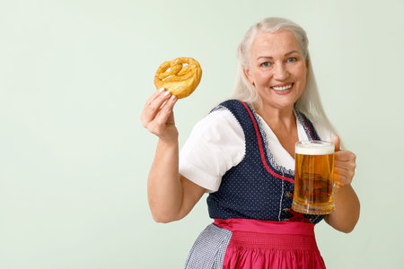 Adorable woman with beer and pretzel on color backgroundの写真素材