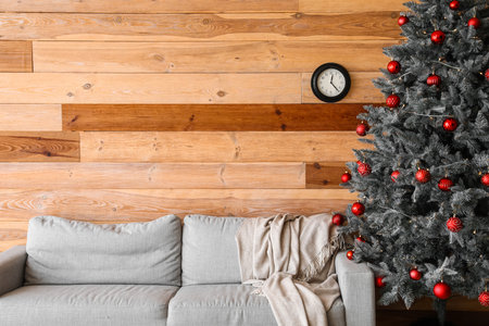 Modern interior with Christmas tree, sofa and black clock on wooden wallの写真素材