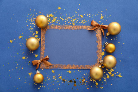 Composition with blank picture frame and Christmas balls on blue backgroundの写真素材