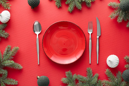 Beautiful table setting with Christmas balls and fir branches on red backgroundの写真素材