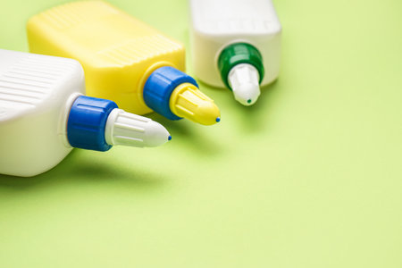 Bottles of glue on green background, closeup