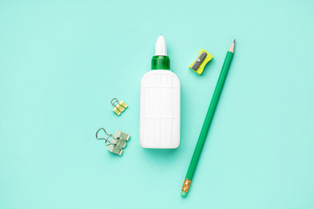Bottle of glue, sharpener, paper clips and pencil on color backgroundの写真素材