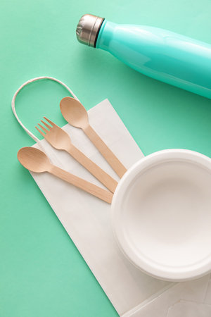 Eco tableware, paper bag and bottle on green backgroundの写真素材