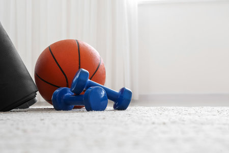 Dumbbells and balls on floor in light roomの写真素材