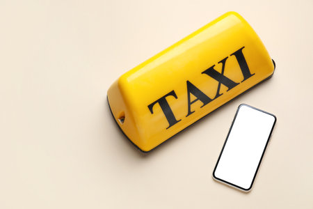 Yellow taxi roof sign and mobile phone on beige backgroundの写真素材
