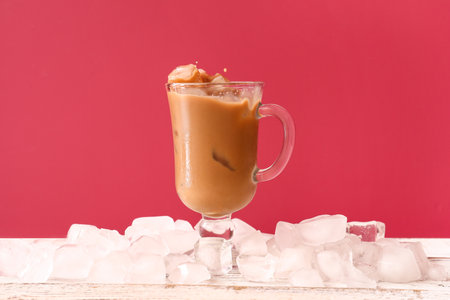 Glass cup of delicious iced coffee with splashes on table