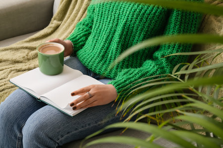 Woman with cup of coffee and book at home, closeupの写真素材