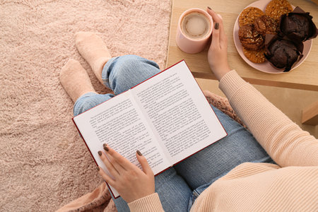 Woman with cup of coffee reading book at homeの写真素材