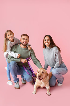 Happy parents with little daughter and Labrador dog on pink backgroundの写真素材