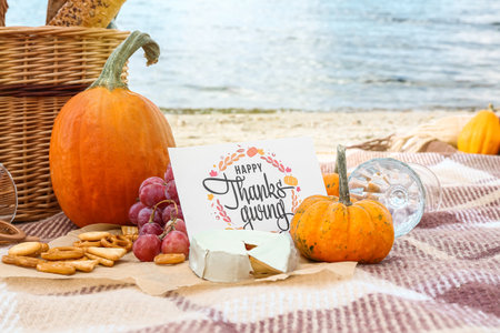 Pumpkin, cheese and card with text HAPPY THANKS GIVING on beachの写真素材