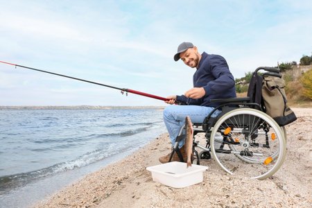 Man in wheelchair fishing on riverの写真素材