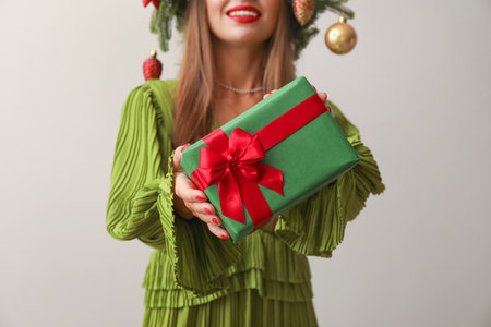 Pretty young woman with Christmas gift on beige background, closeupの写真素材
