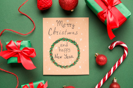 Gifts, decor, greeting card with text MERRY CHRISTMAS AND HAPPY NEW YEAR on green backgroundの写真素材