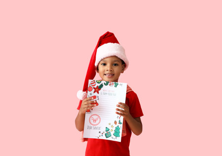 Cute African-American boy with letter to Santa on color backgroundの写真素材
