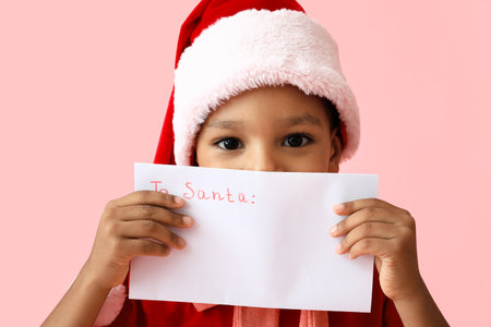 Cute African-American boy with letter to Santa on color backgroundの写真素材