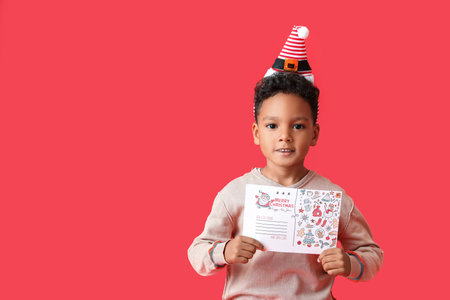 Cute African-American boy with letter to Santa on color backgroundの写真素材