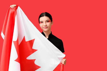 Beautiful young woman with Canadian flag on red backgroundの写真素材