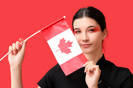 Beautiful young woman with Canadian flag on red backgroundの写真素材
