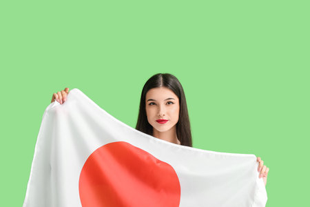 Beautiful young woman with flag of Japan on color backgroundの写真素材