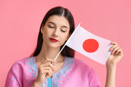 Beautiful young woman with flag of Japan on color backgroundの写真素材