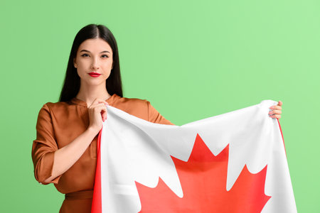 Beautiful young woman with Canadian flag on green backgroundの写真素材