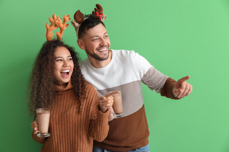 Happy couple with hot chocolate on color backgroundの写真素材