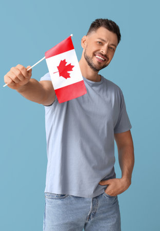 Happy young man with flag of Canada on blue backgroundの写真素材