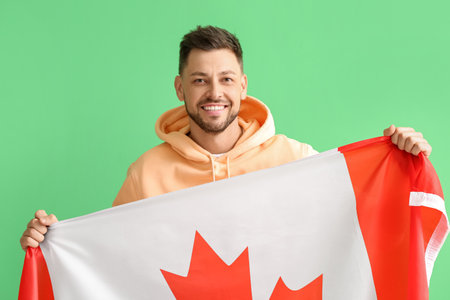 Happy young man with flag of Canada on green backgroundの写真素材