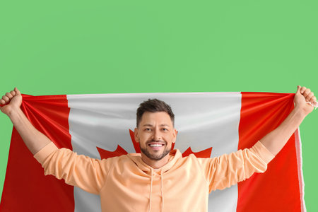 Happy young man with flag of Canada on green backgroundの写真素材