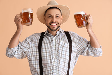 Young man in traditional German clothes with beer on beige backgroundの写真素材