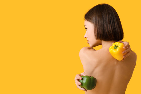 Naked young woman with bell pepper on color background. Vegan Dayの写真素材
