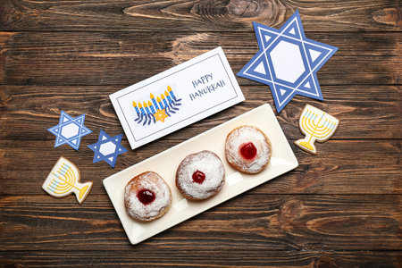 Different symbols of Hanukkah and greeting card with donuts on wooden backgroundの写真素材