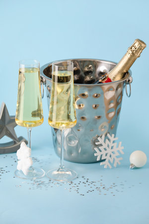 Glasses of champagne, ice bucket with bottle and Christmas decorations on color backgroundの写真素材