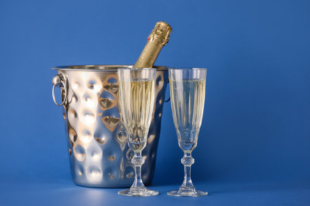 Ice bucket with bottle and glasses of champagne on color backgroundの写真素材
