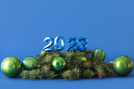 Figure 2023 with Christmas balls and fir branches on blue backgroundの写真素材