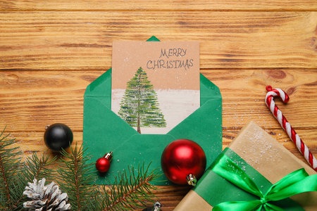 Composition with greeting card, Christmas decorations and gift on wooden background
