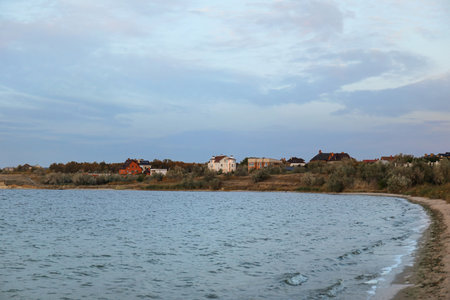 View of beautiful lake, shore and houses on cloudy dayの写真素材