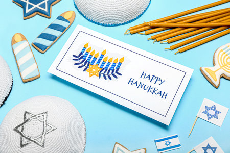 Different symbols of Hanukkah and greeting card on color background