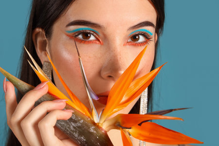 Beautiful young woman with strelitzia flower on color backgroundの写真素材