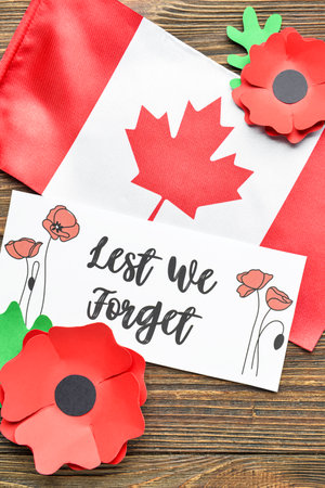 Paper poppy flowers, card and flag of Canada on wooden background. Remembrance Dayの写真素材