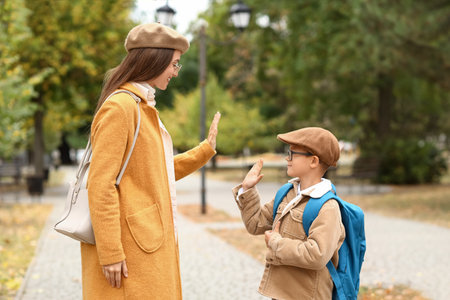 Woman and her little son giving each other high-five before schoolの写真素材