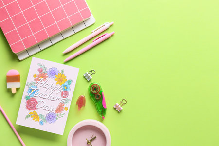 teacher's day concept. School supplies, greeting card and alarm clock on green background, top viewの写真素材