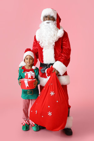 Cute little elf with Santa Claus and gifts on pink backgroundの写真素材