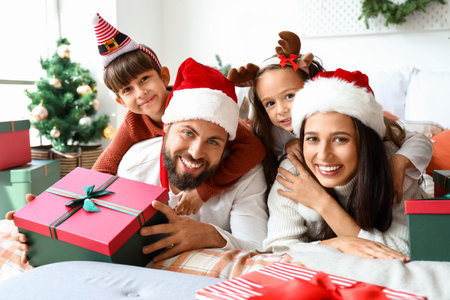 Happy family with Christmas gifts lying on bedの写真素材