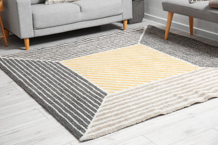 Soft stylish carpet on light wooden floor in living room