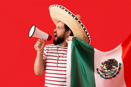 Handsome man in sombrero, with Mexican flag and megaphone on color backgroundの写真素材