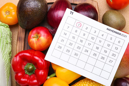 Fresh vegetables and calendar with marked date NOVEMBER 1 on color background, closeup. World Vegan Day conceptの写真素材