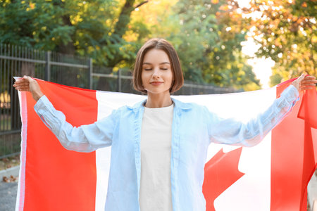Beautiful young woman with flag of Canada outdoorsの写真素材