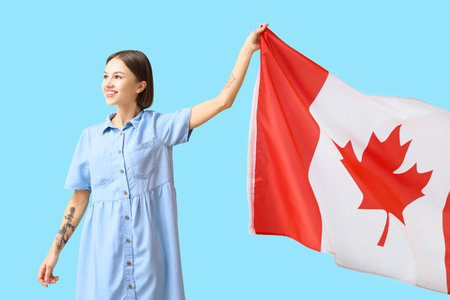 Beautiful young woman with Canadian flag on blue backgroundの写真素材